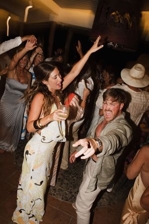 Guests dance energetically at an outdoor evening wedding reception party celebration.