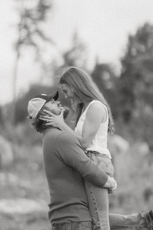 Black and white photo of a romantic couple embracing and almost kissing outdoors.