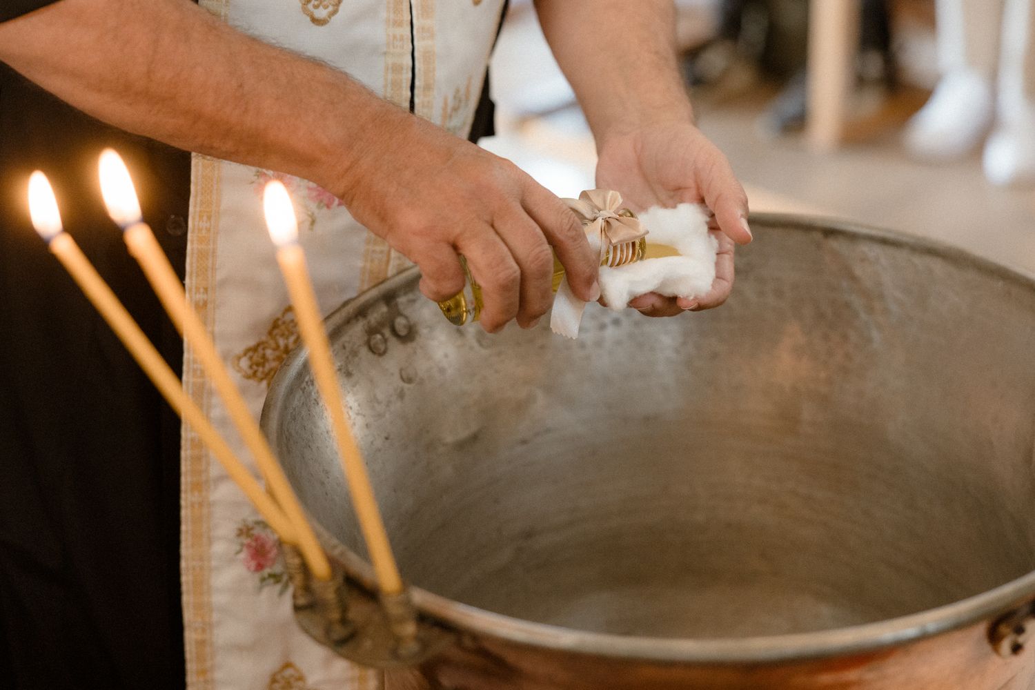 Newborn baby being bathed in a metal bowl, gently supported by adult hands during first bath.