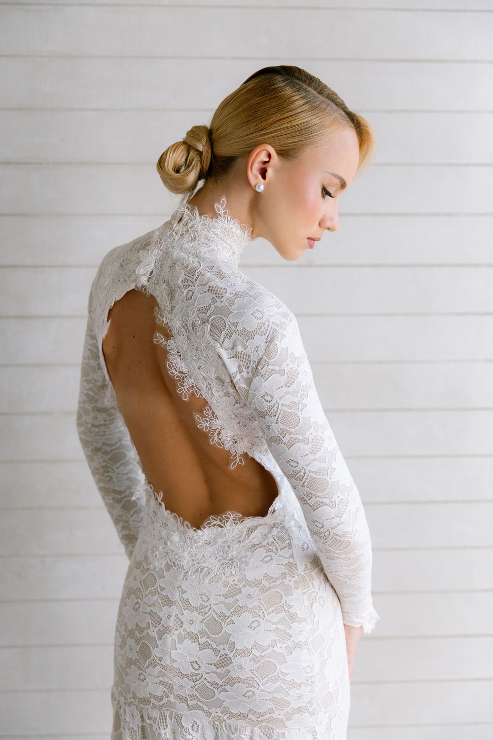 Close-up of bride in long-sleeve lace wedding dress featuring a sophisticated open back design.