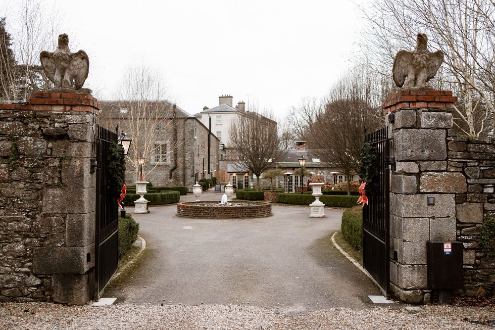 Elegant stone gate entrance to a historic Irish manor house wedding venue with gravel driveway.