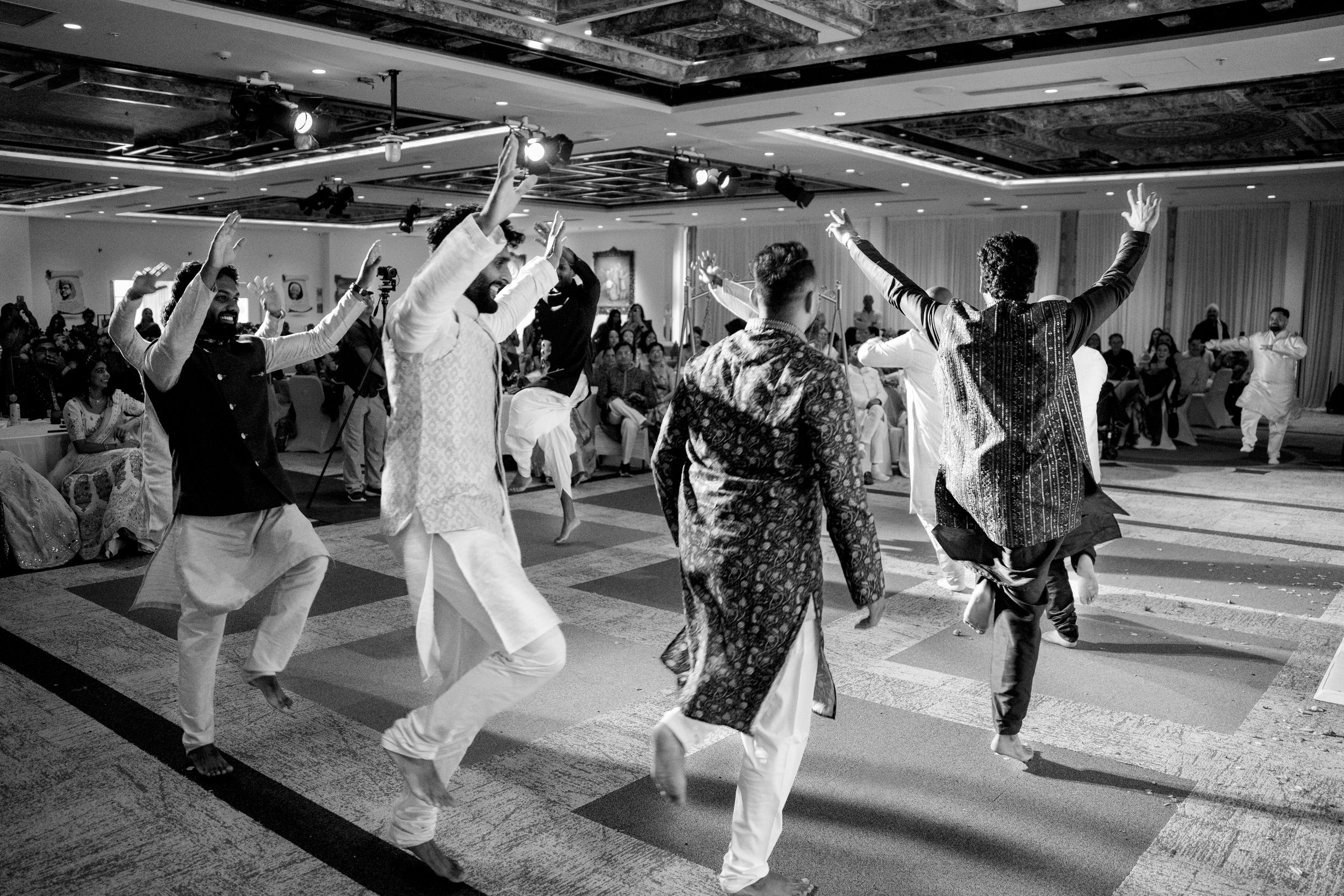 Guests dancing energetically in traditional South Asian attire at a wedding reception in a grand ballroom.