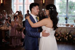 Bride and groom share their first dance at an elegant wedding reception with guests applauding in the background.
