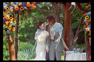Bride and groom share an intimate moment under a floral arch adorned with sunflowers during outdoor wedding ceremony.