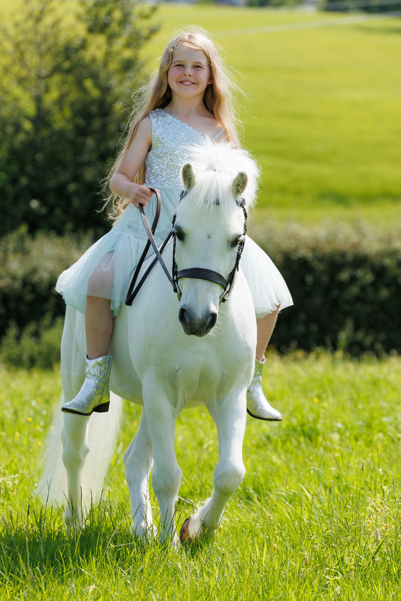 A brown horse and rider in a white sweater pose together against autumn foliage in soft natural lighting.