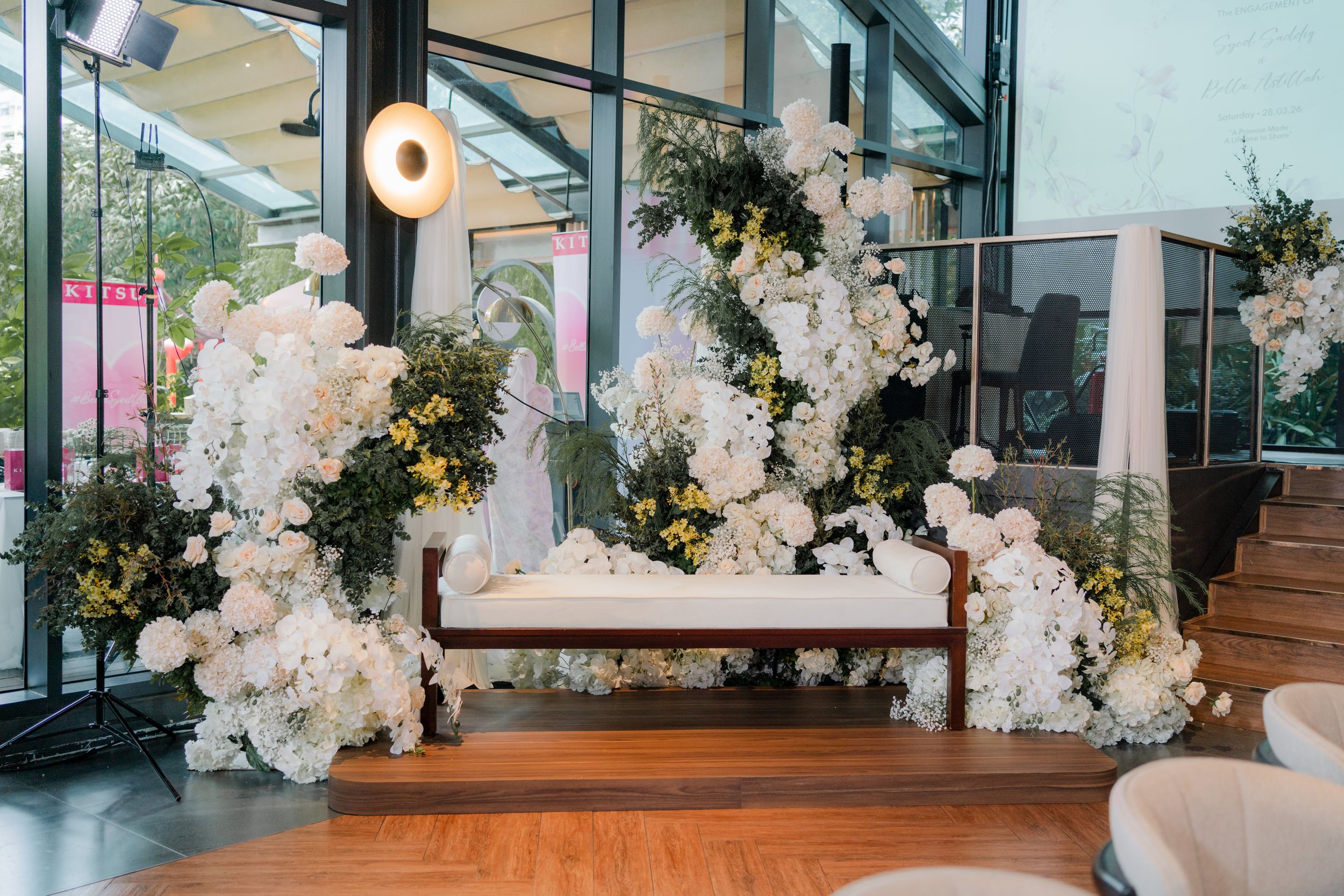Elegant wedding sweetheart table adorned with lush white floral arrangements and greenery in a modern venue.