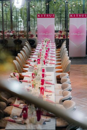 Elegant Kitsui branded Valentine's dinner event with long white tables, pink decor, and floral centerpieces in a stylish venue.