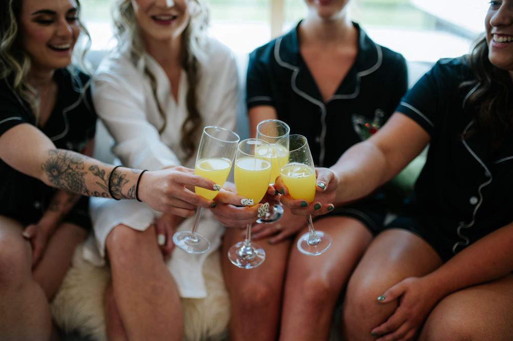 Bridesmaids in matching pajamas toasting with mimosas at a bridal party getting ready celebration.