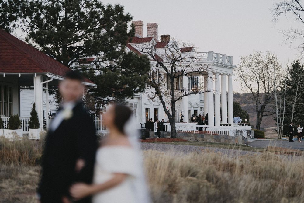 Bride and groom pose in front of a grand white colonial wedding venue with columns at dusk.