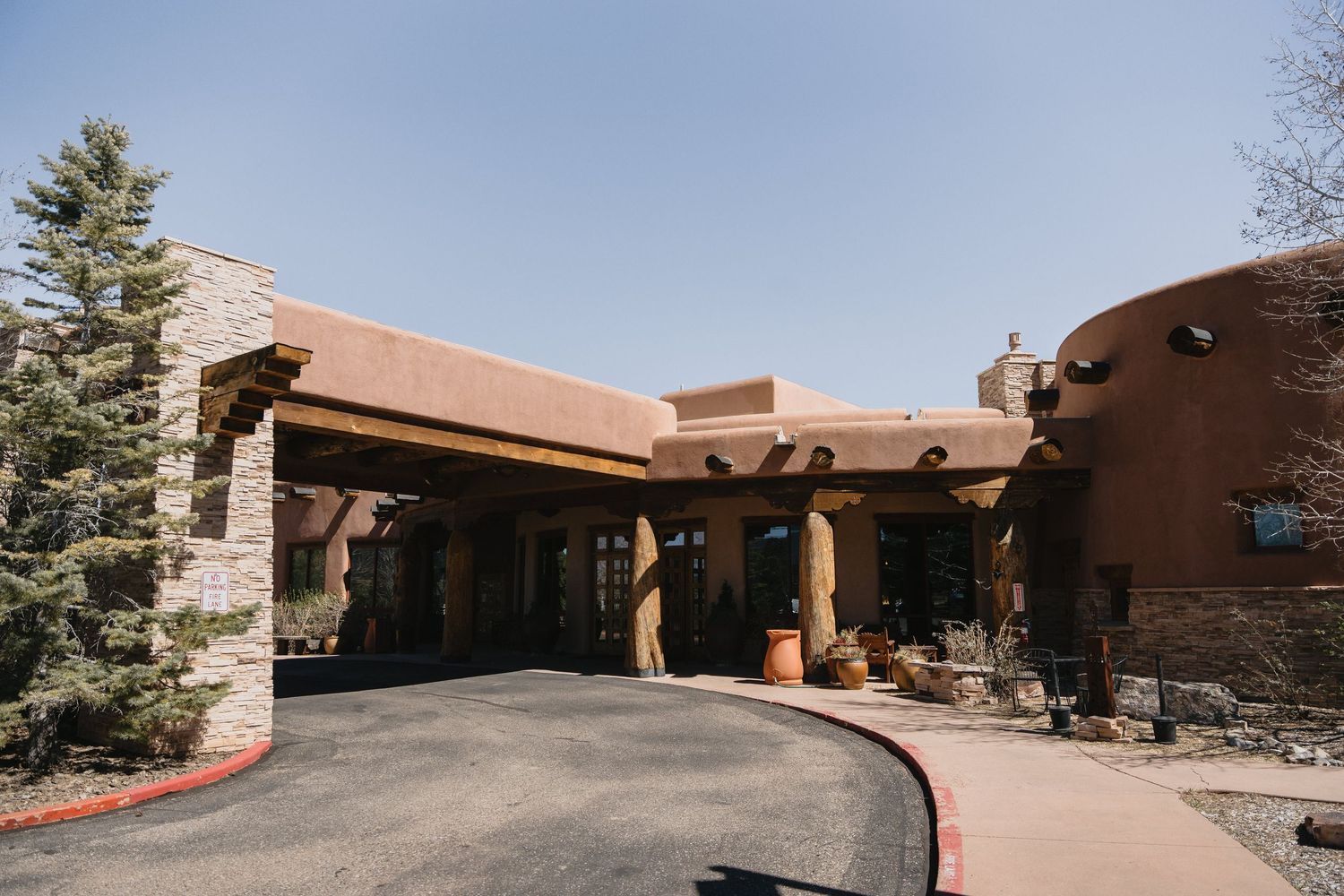 Exterior view of a Southwestern-style adobe building with stone accents and a curved driveway.