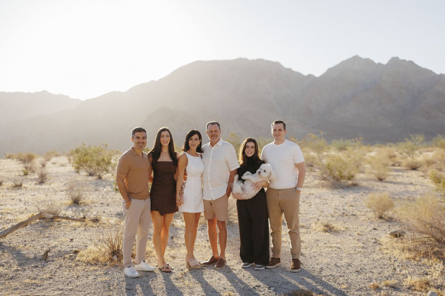 Family of four posing on desert rocks at Joshua Tree National Park with boulders and Joshua trees in background.