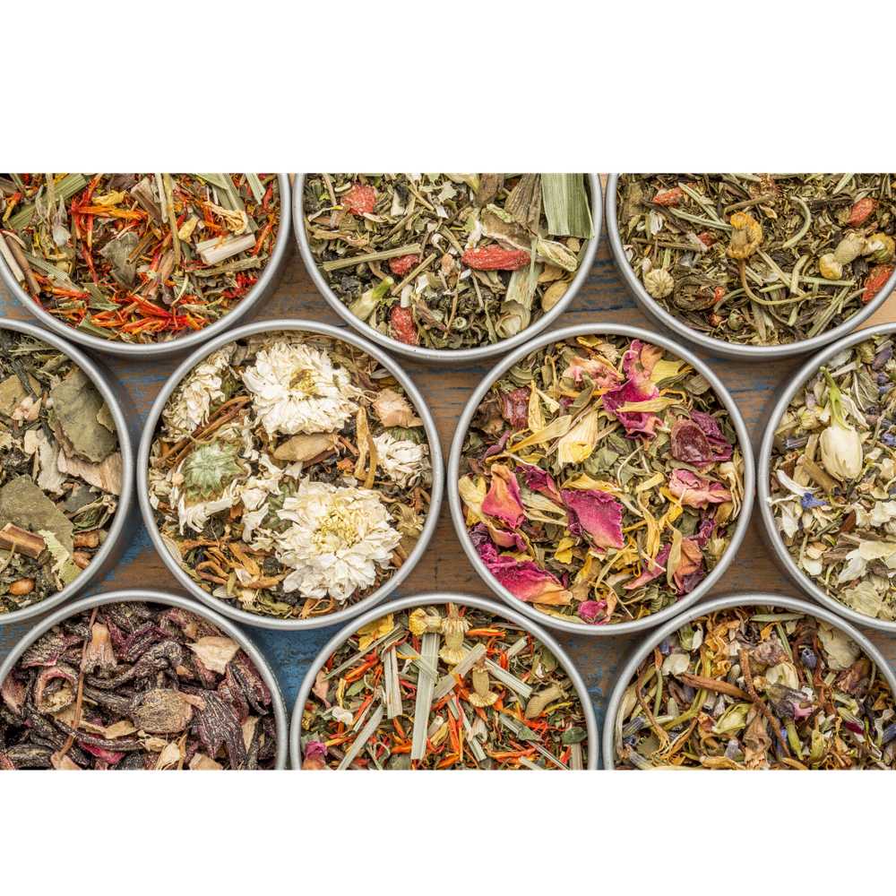 Assorted herbal loose leaf teas displayed in round metal tins, featuring dried flowers, herbs, and botanicals.
