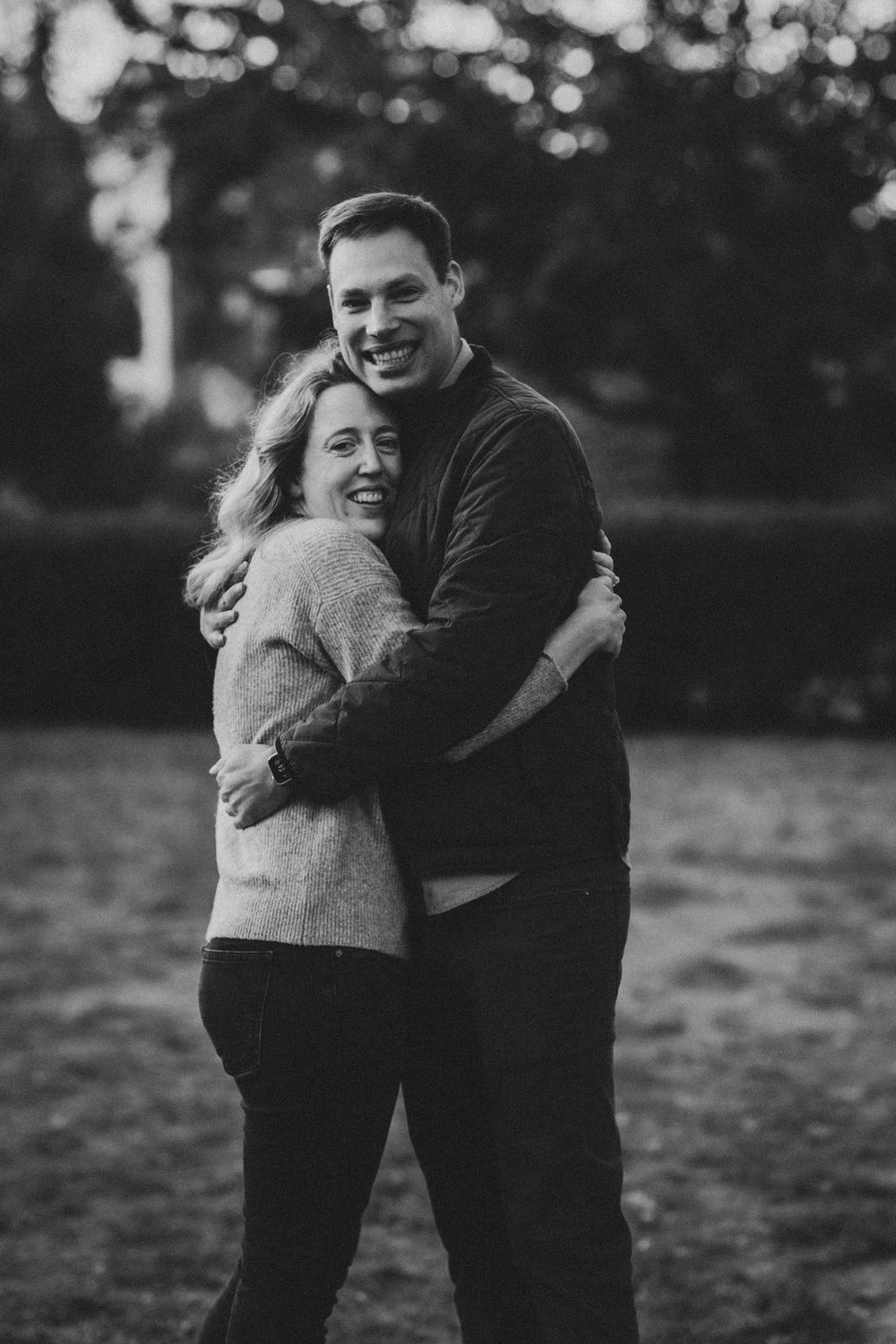 Happy couple embracing and smiling outdoors in a black and white portrait photo.