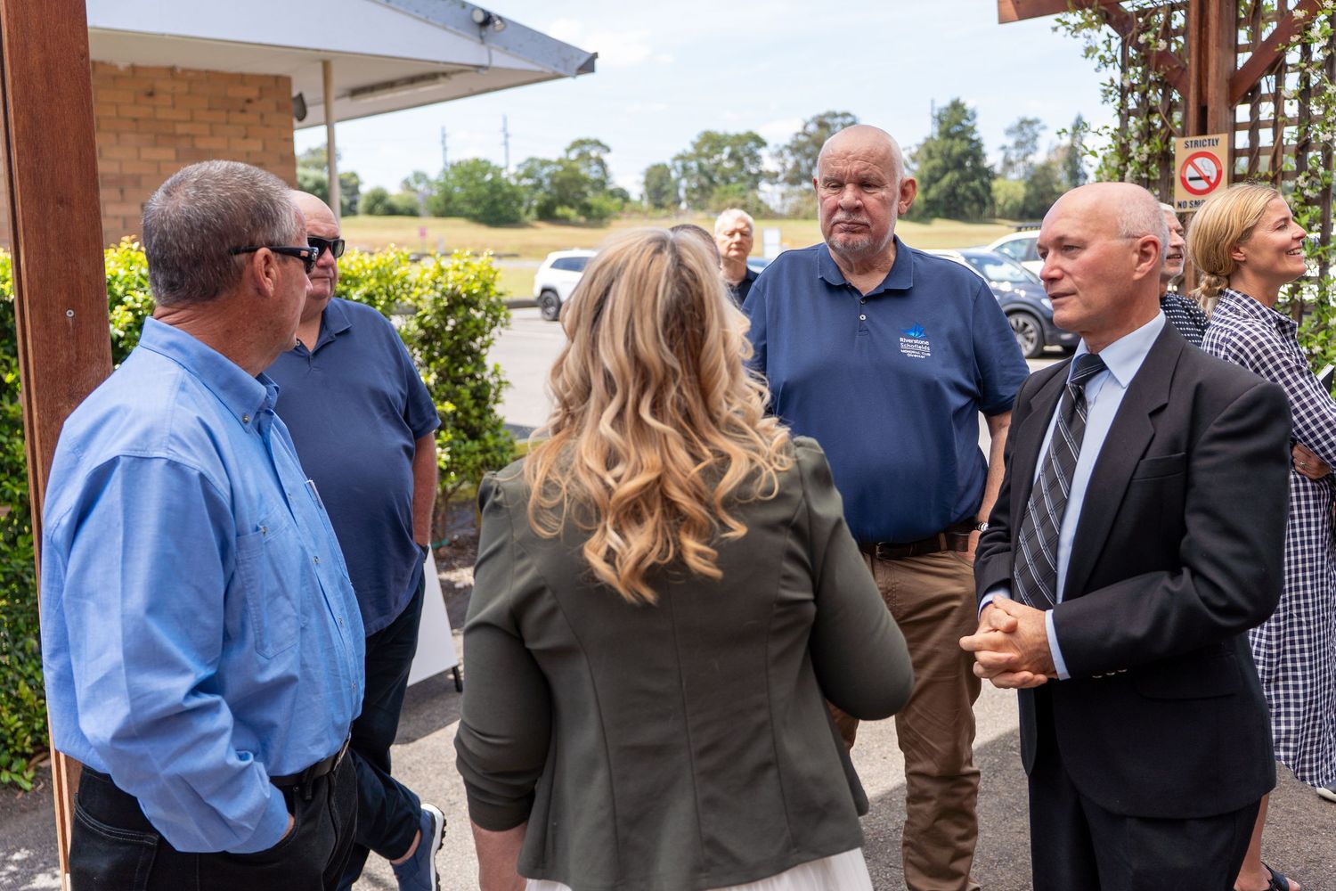 Group of professionals networking and conversing outside a building on a sunny day.