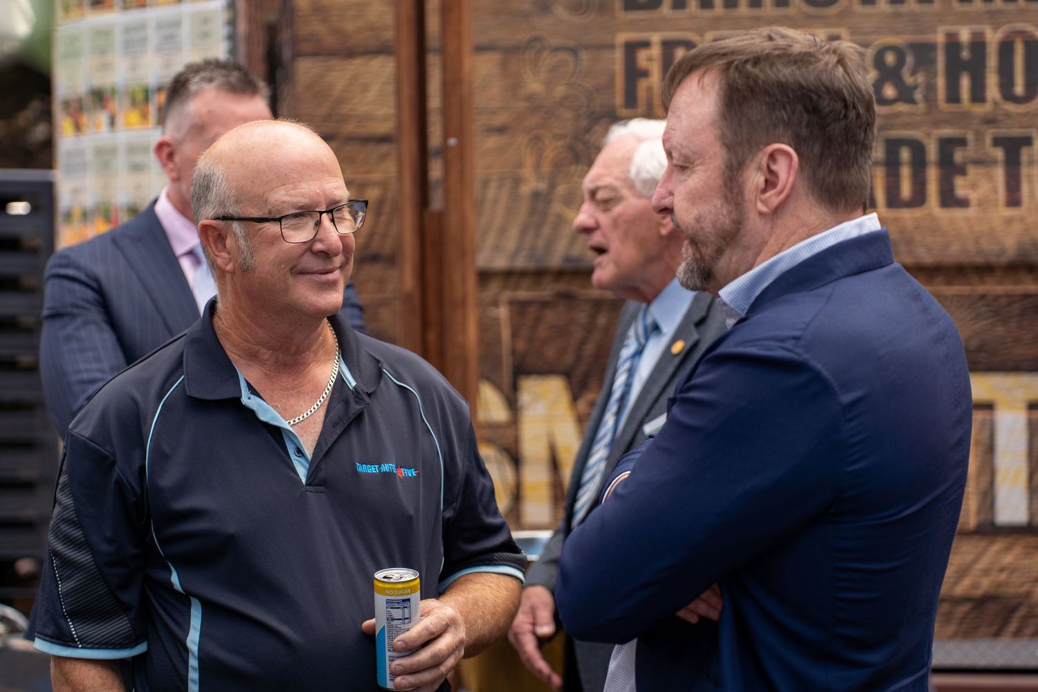 Three men in business casual attire conversing at an outdoor networking event.
