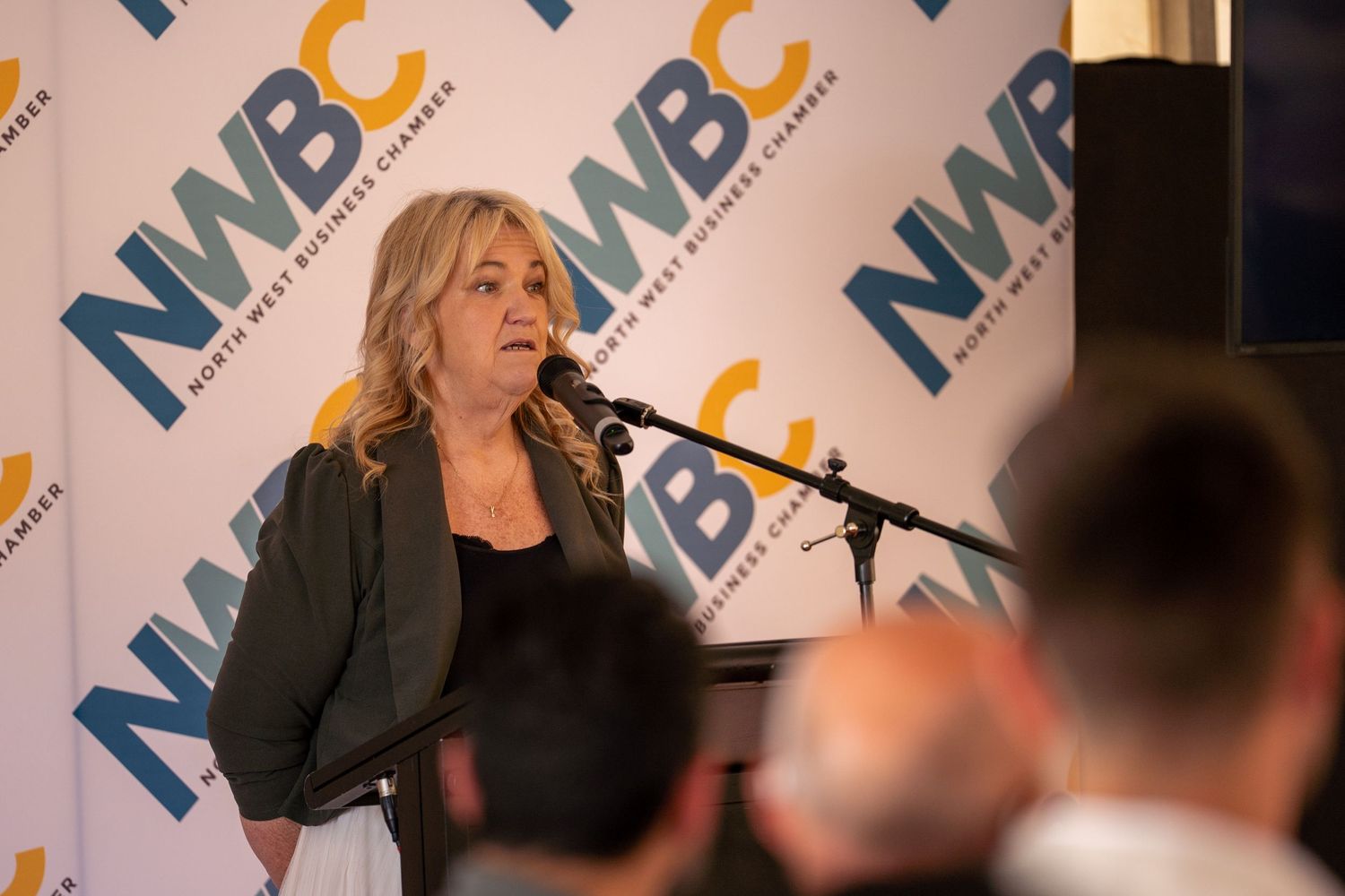 Blonde woman speaking at a podium at a North West Business Chamber NWBC event.