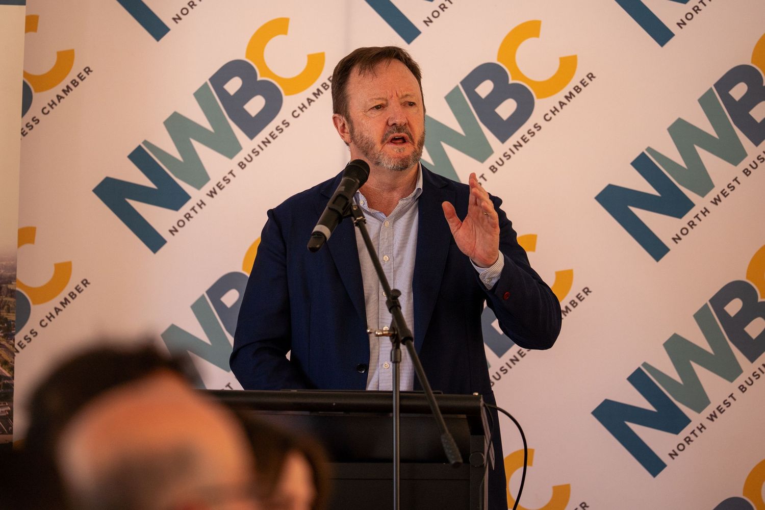 Man in blue blazer speaking passionately at a North West Business Chamber NWBC event.