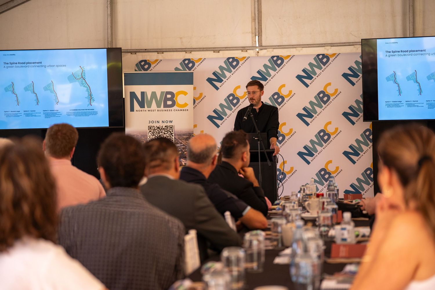 Speaker presenting to seated audience at a North West Business Chamber NWBC conference.
