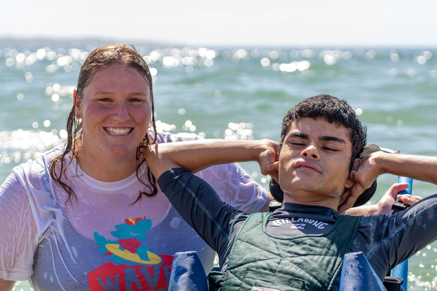 Smiling female surf instructor posing with a young boy at the beach after a surf lesson.