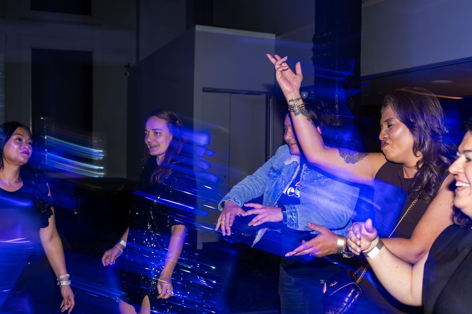 Women dancing under blue lights at a lively evening party.