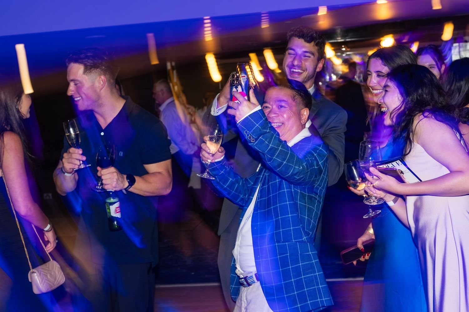 Group of guests celebrating with drinks raised at an indoor party.