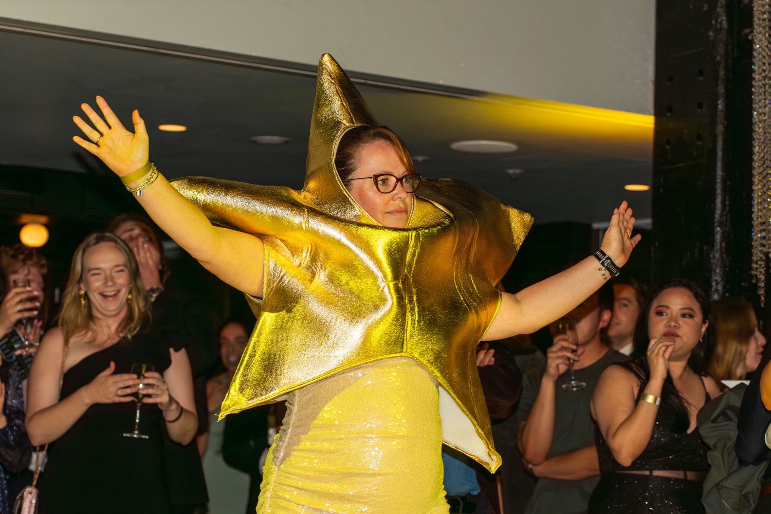 Person in a dramatic gold star costume dancing at an event.
