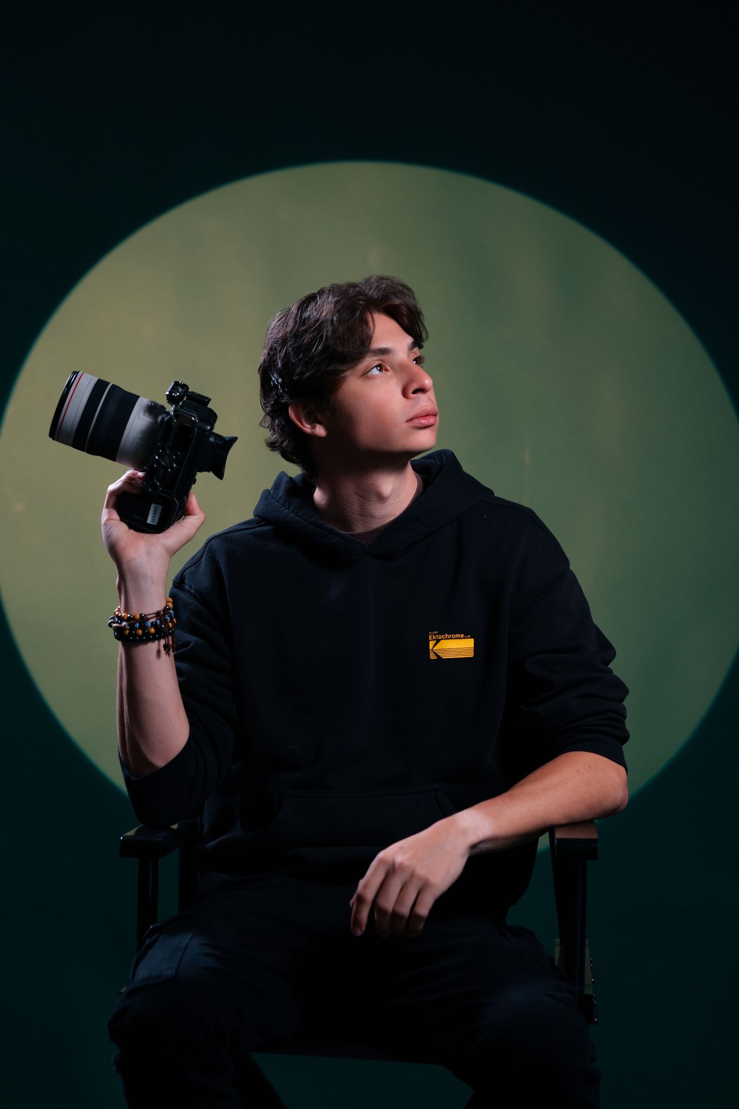 Portrait of Mannyportraits holding a camera against a green studio backdrop