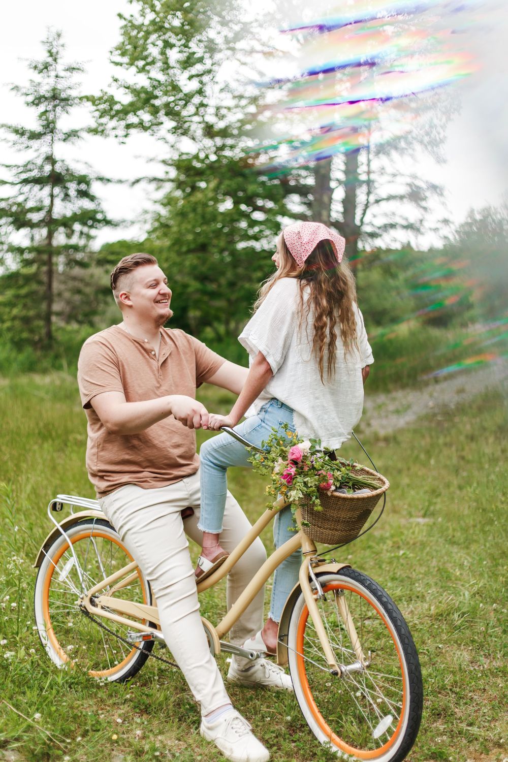 Happy couple holding hands by a vintage bicycle with flower basket in a green park setting.