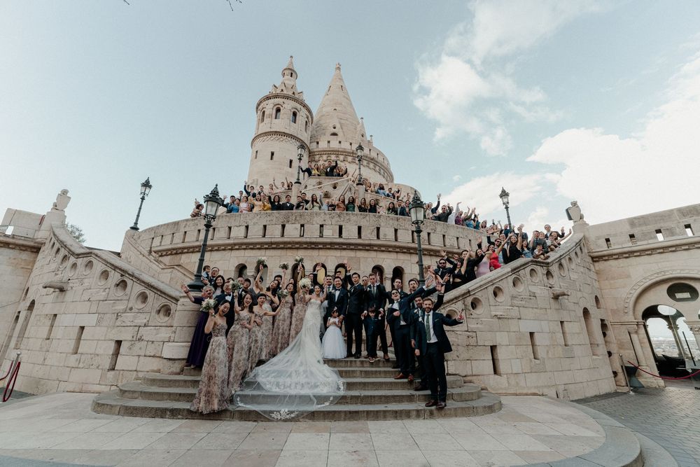 Wedding party posing on grand castle steps with bride and groom at Fishermans Bastion Budapest.