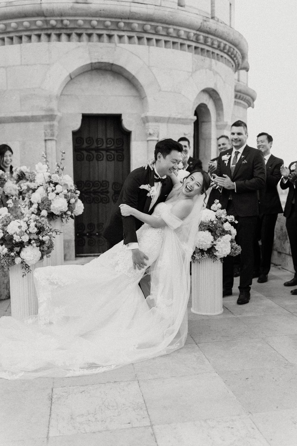 Joyful bride and groom sharing a dip kiss after their ceremony at a historic stone castle venue.