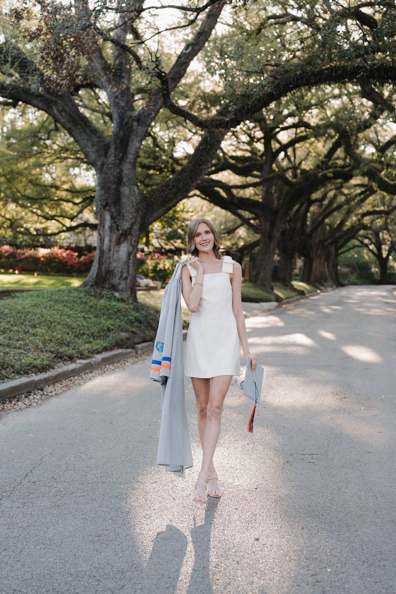 College Park High School senior girl, wearing short white dress, standing under oak tree canopy in Houston Texas.