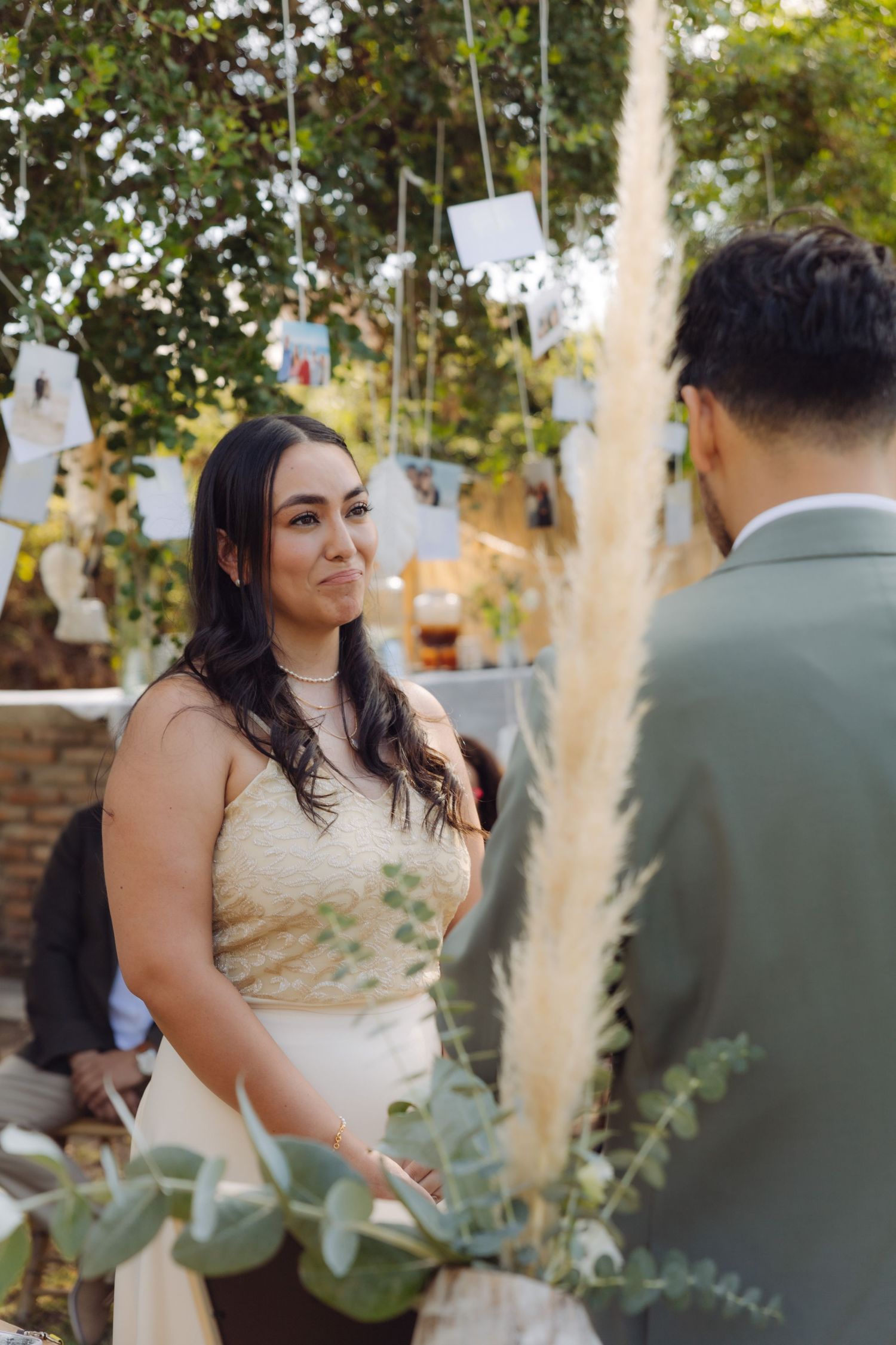 Emotional bride holds back tears while exchanging vows with groom at outdoor garden wedding.