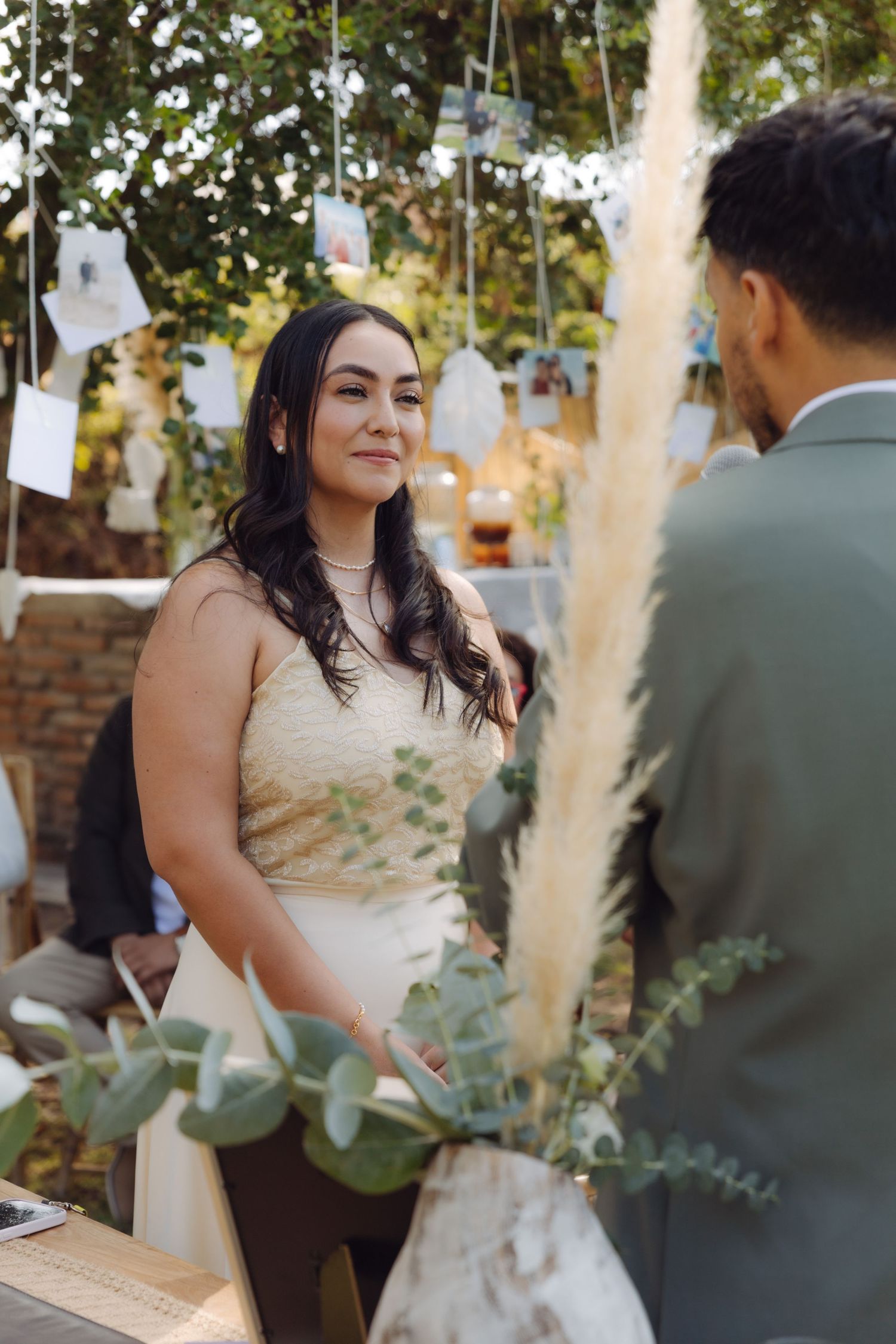 Bride gazes lovingly at groom during outdoor wedding ceremony surrounded by eucalyptus greenery.