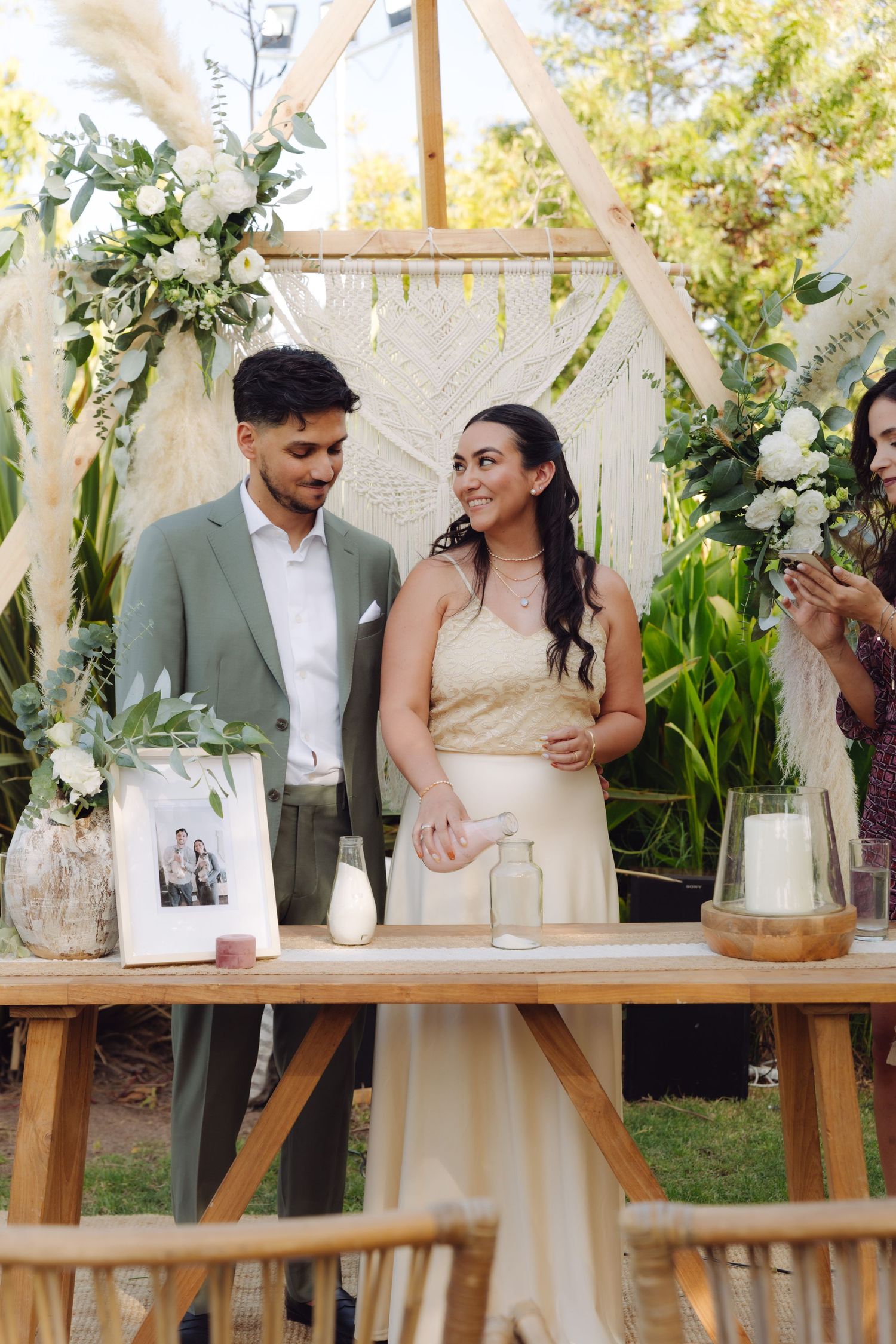 Bride and groom smiling together at wooden altar during elegant outdoor garden wedding.