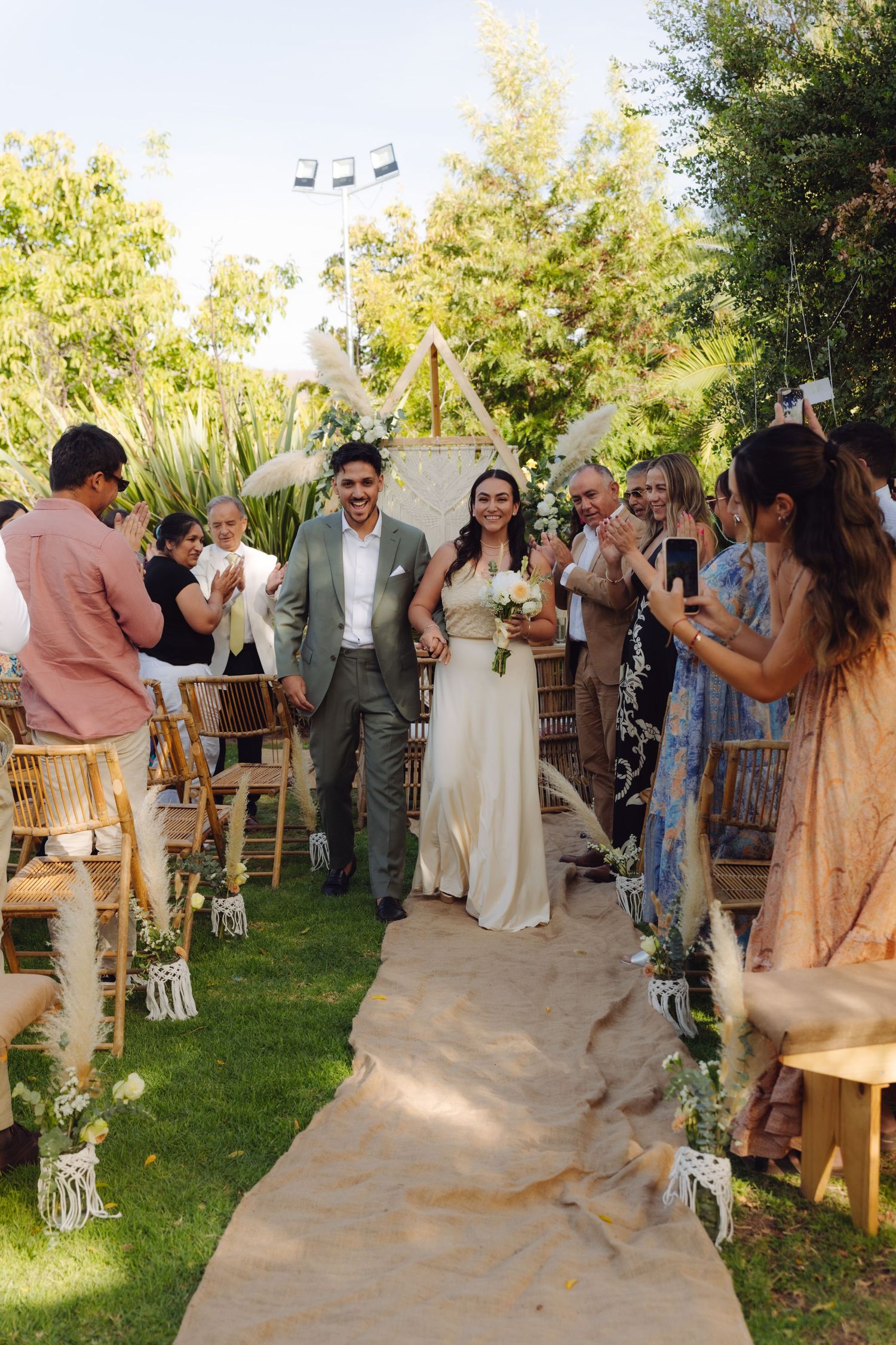 Newlyweds walking down the aisle after wedding ceremony as guests cheer and celebrate.