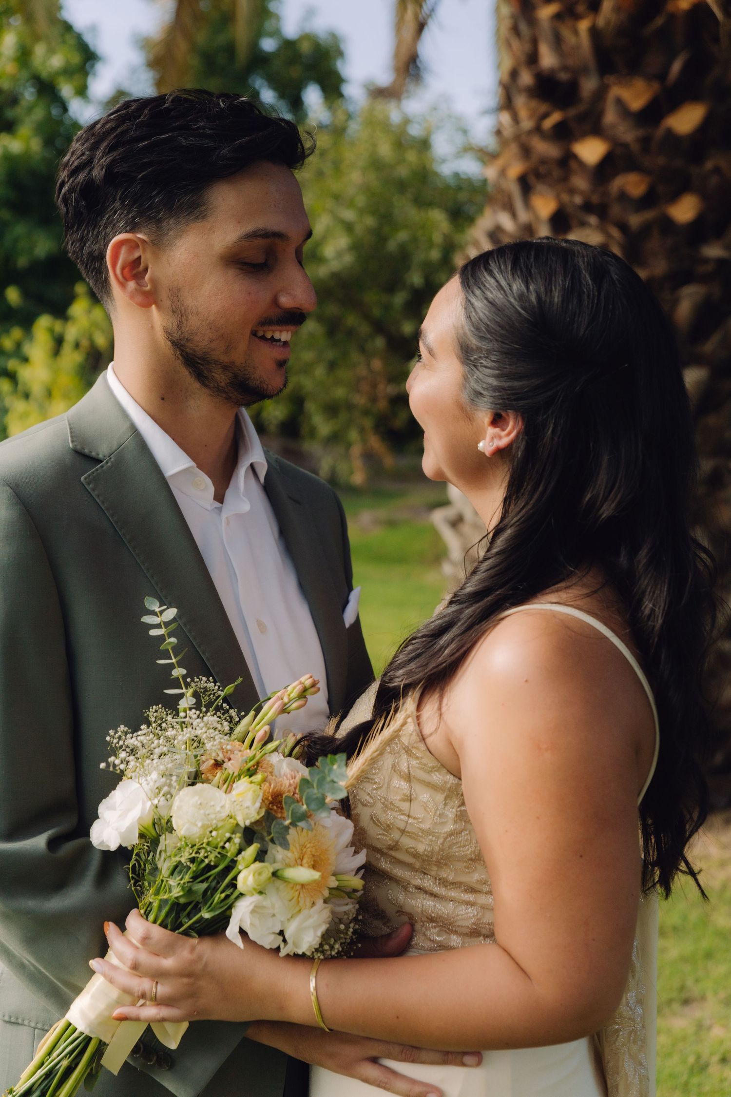 Happy couple shares a joyful moment together as bride holds colorful wedding bouquet in garden.
