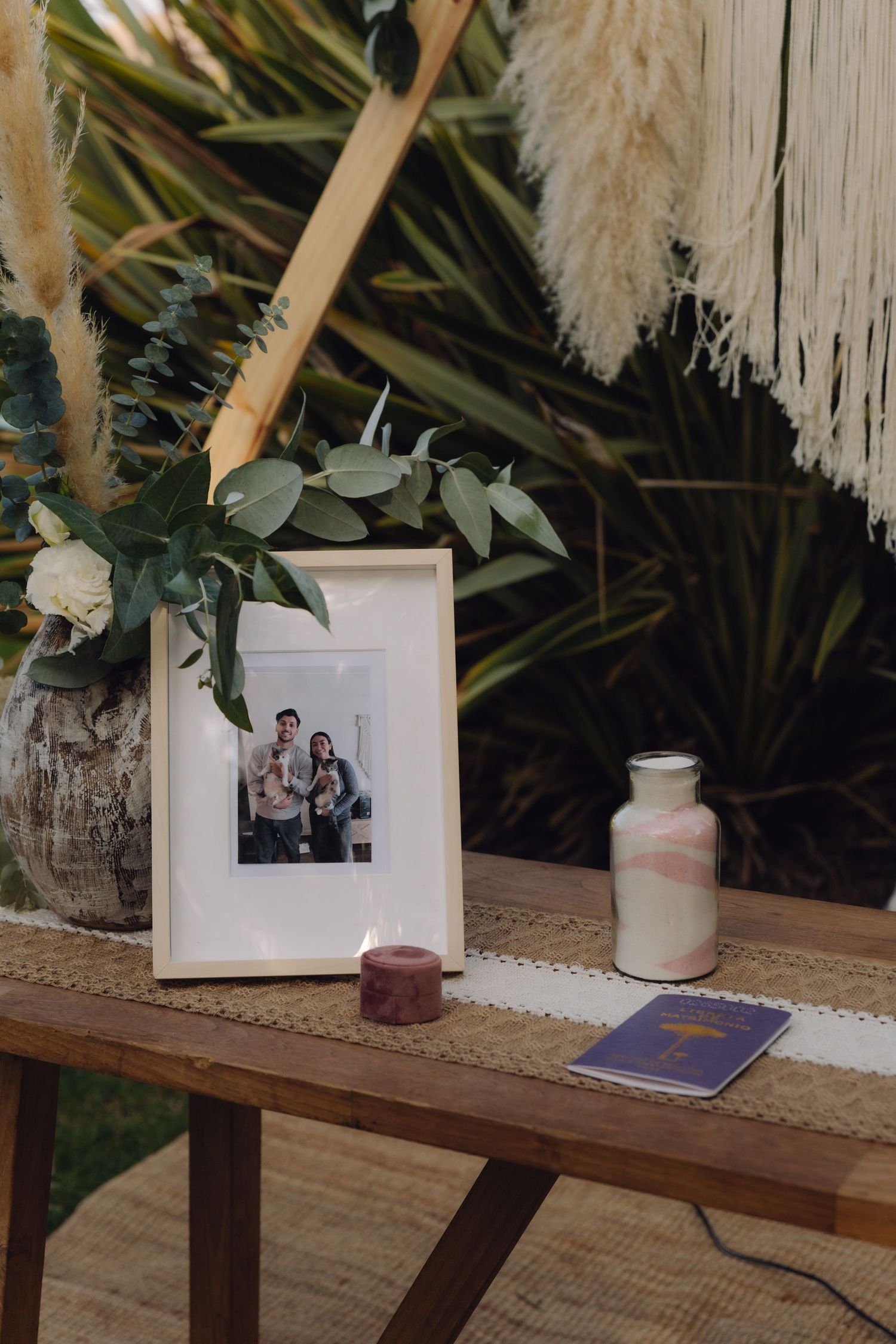 Framed family photo displayed on wooden table with candle and sand ceremony vases.