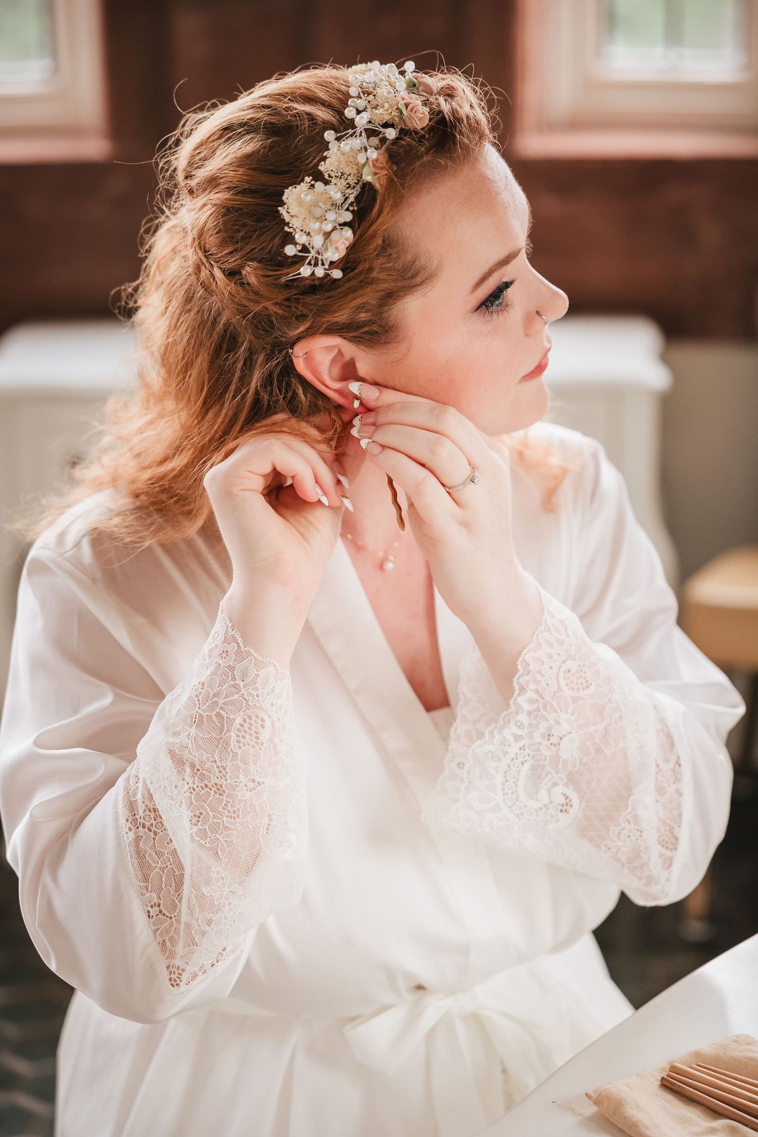 Bride putting on her sword-shaped earring during the final moments of wedding day preparations.