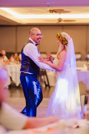Bride and groom share their first dance at wedding reception, bride wearing floral crown and veil.
