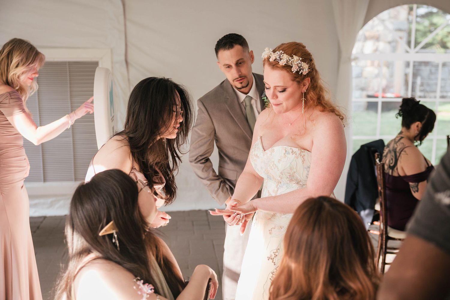 Bride showing her ring to a small group of guests gathered closely around her.