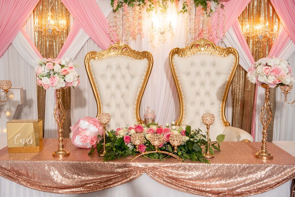 Elegant quinceanera sweetheart table with gold throne chairs, pink floral arrangements, and rose gold sequin tablecloth.