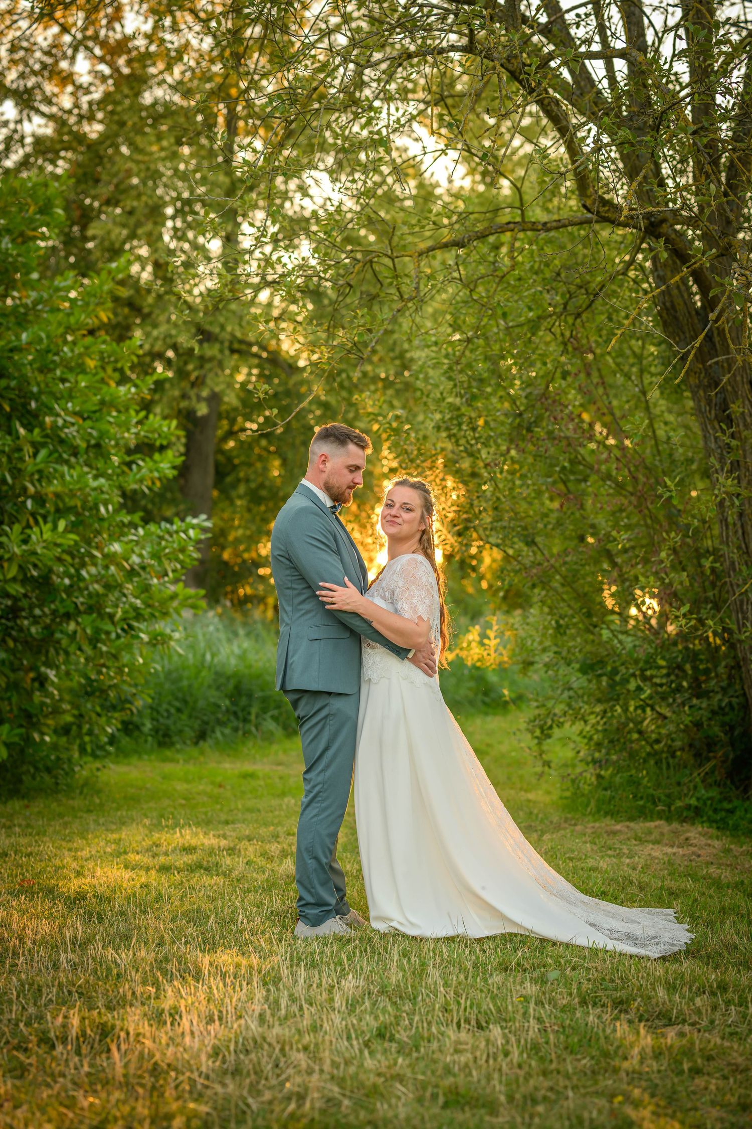 Photo de mariage en couleurs chaudes d'un couple sous un arbre à la ferme de Bertinchamps dans le Brabant Wallon en Belgique