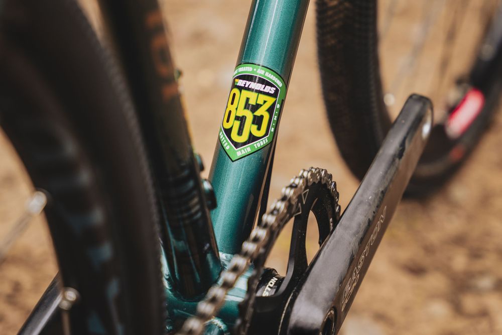 Close-up of a teal mountain bike frame featuring a Reynolds 853 steel tubing decal with chain and components visible.