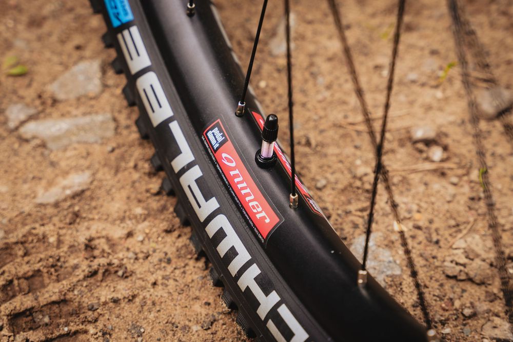 Close-up of a mountain bike wheel with Schwalbe tire and carbon rim on a dirt trail.