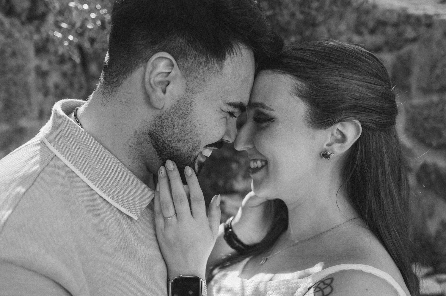 Black and white photo of a romantic couple sharing an intimate moment, smiling and facing each other closely.