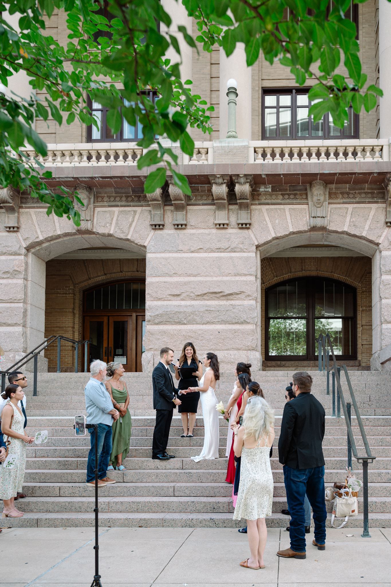 Bride and groom holding hands on the granite steps of the historic 1910 Harris County Courthouse.