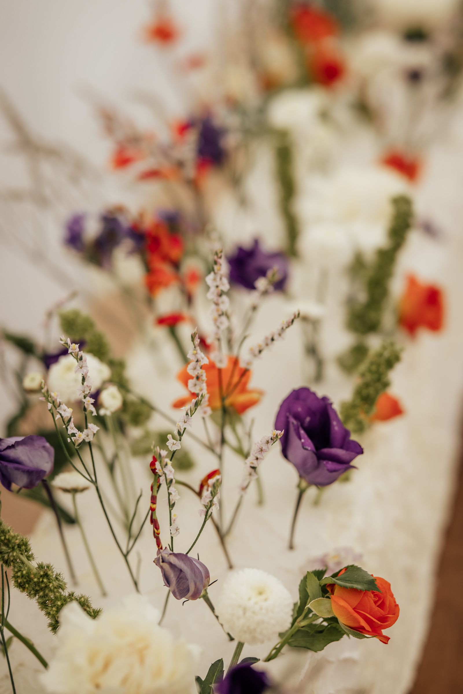 Colorful wildflower arrangement featuring purple, orange, and white blooms on a decorated table.