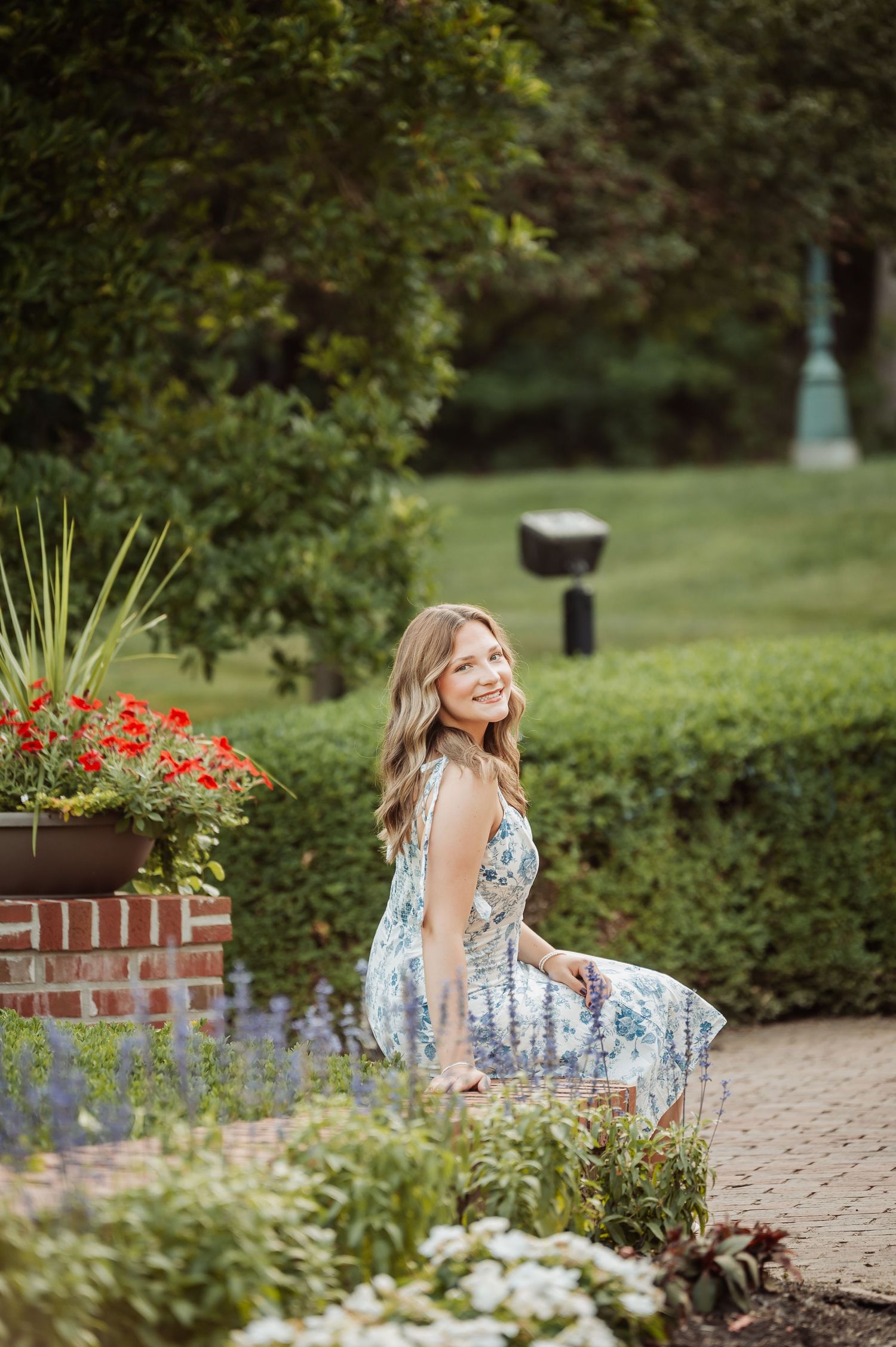 Young woman smiling among sunflowers, hand in hair, golden bokeh background, outdoor portrait photography.