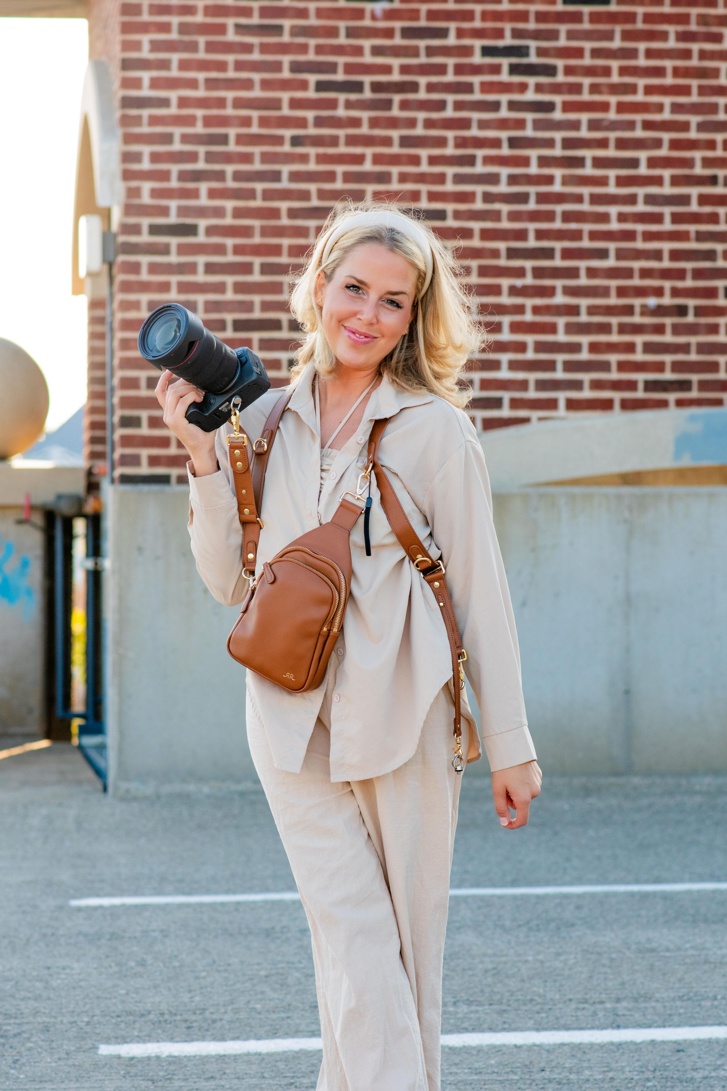 Candid outdoor portrait of photographer Danielle Taylor with her camera, showcasing her natural, documentary lifestyle media brand.