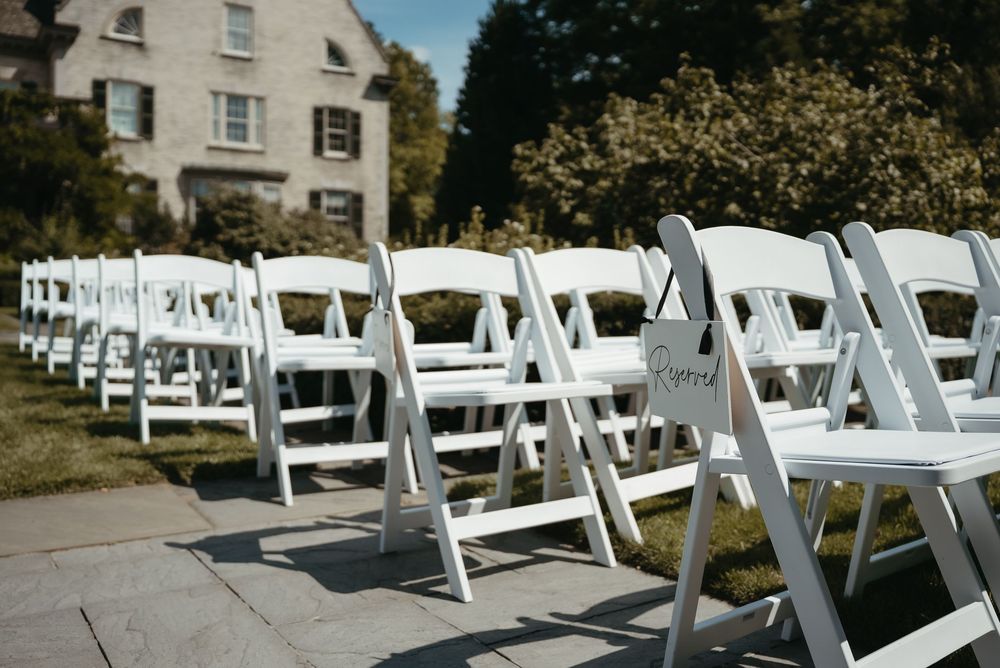 White folding chairs arranged in rows for an outdoor wedding ceremony on a sunny day.